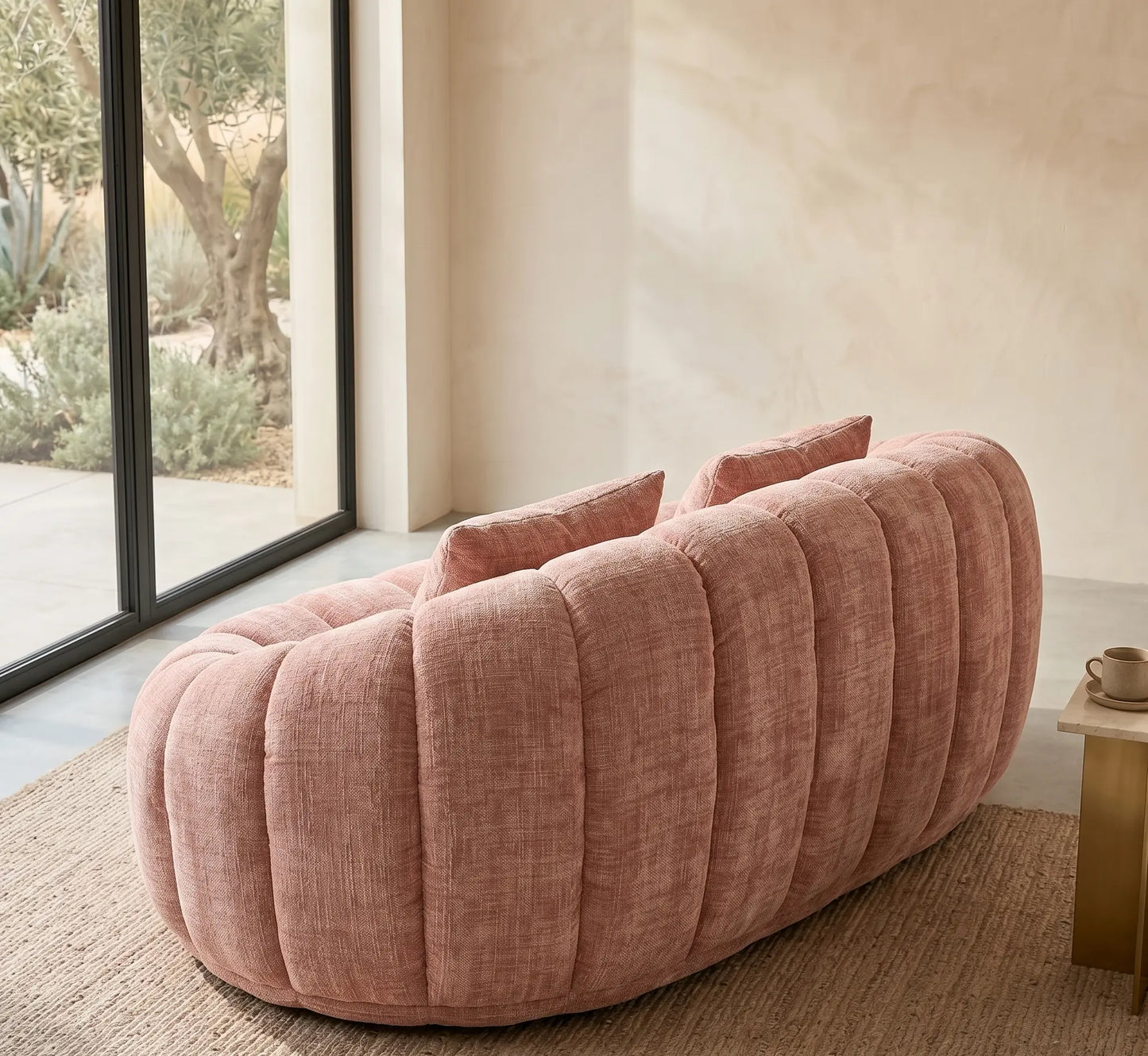 Gros plan détaillé sur l'assise bombée et le dossier d'un canapé pouf panoramique gris anthracite en tissu texturé, montrant la qualité du tissage près d'une fenêtre.