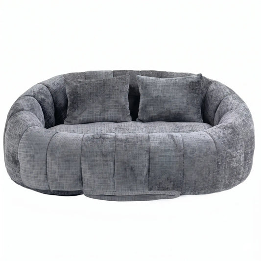 Vue de face d'un grand canapé pouf panoramique gris anthracite en tissu chiné texturé avec deux coussins carrés, design galet sur fond blanc.