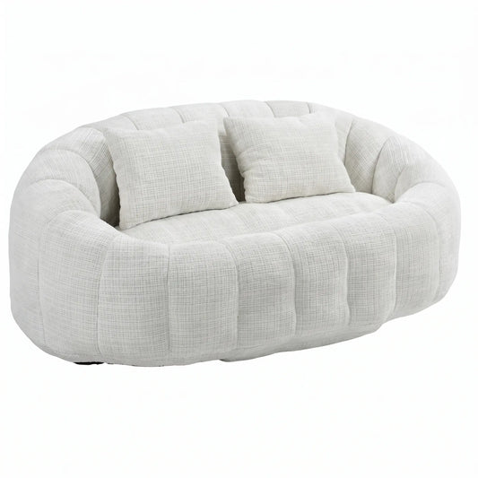 Grand canapé pouf panoramique arrondi blanc crème en tissu texturé effet nuage avec deux coussins assortis sur fond blanc.