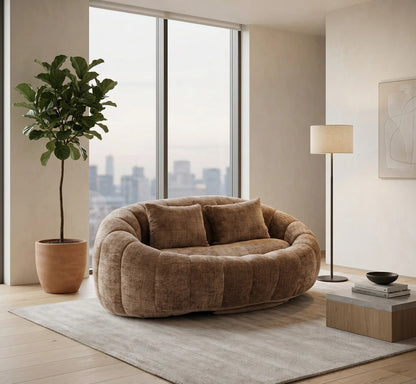 Aménagement de grand salon luxueux avec un canapé pouf panoramique bicolore beige sable et camel, une table basse design et un décor épuré.
