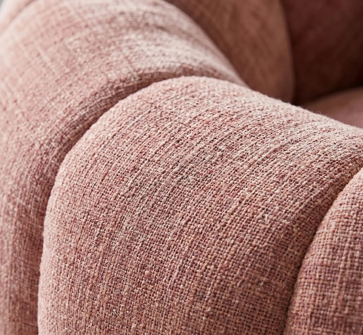 Gros plan détaillé sur le tissu chenille texturé d'un canapé pouf rose terracotta, mettant en avant le tissage artisanal et la douceur du revêtement.